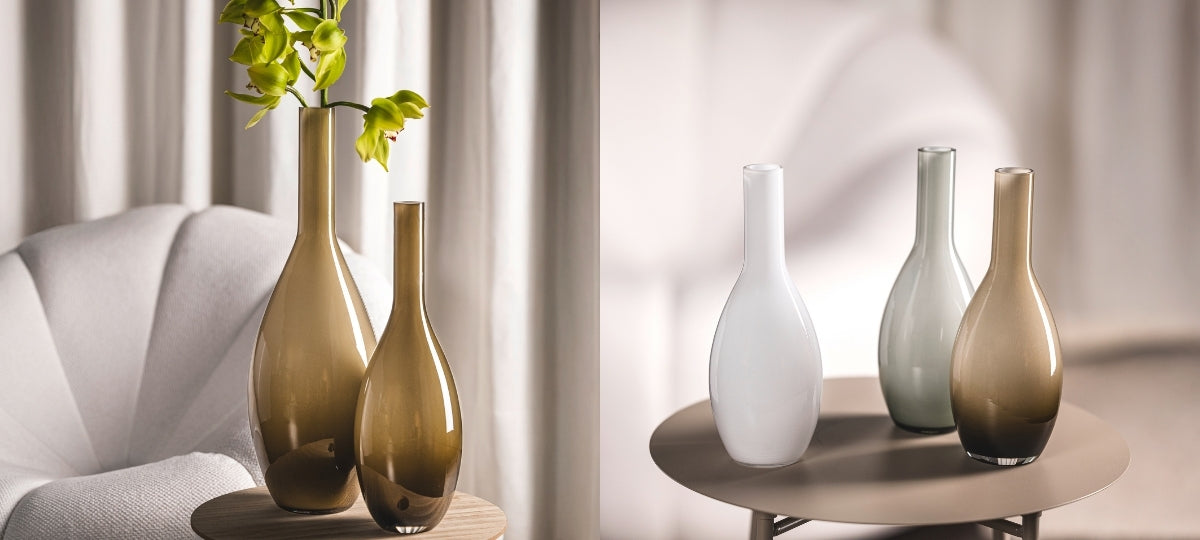 Elegante Glasvasen in Weiß, Beige und Grauton auf Holztisch und Sessel, helles Tageslicht, moderne Wohnambiente