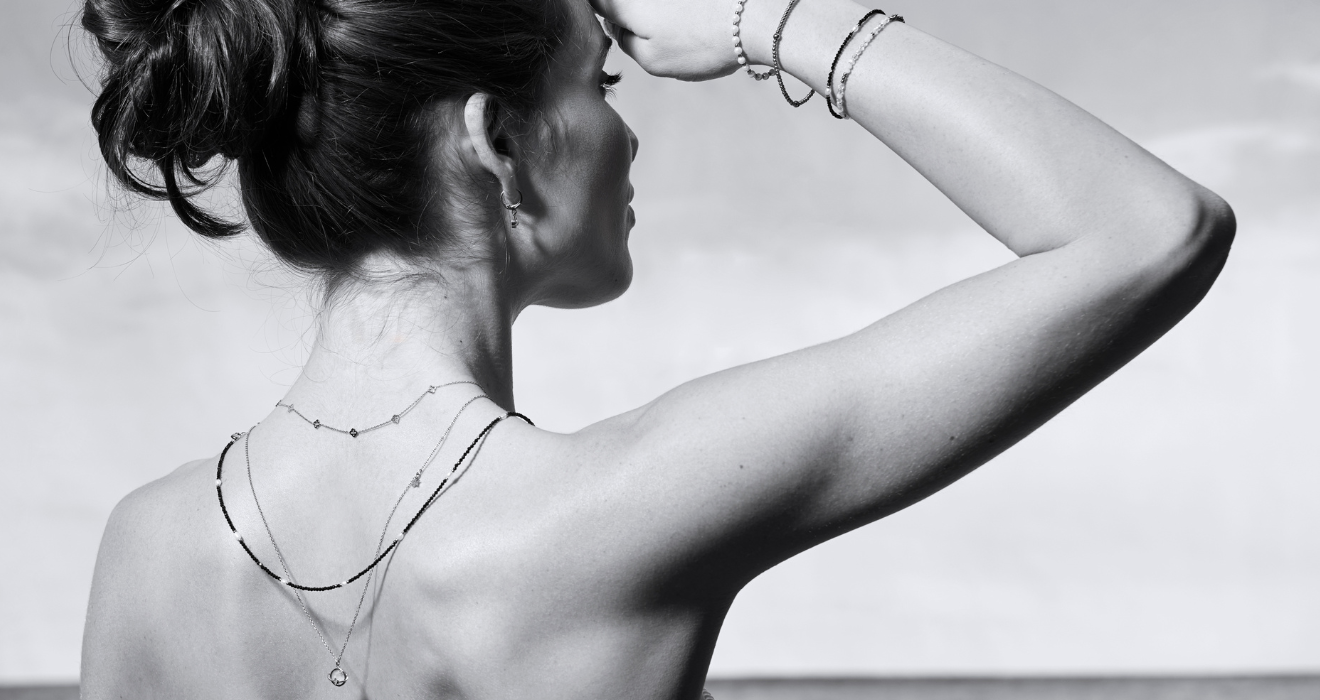 Frau von hinten mit eleganten Schmuckketten und Armbändern, schwarzweißes Portrait, minimalistischer Stil