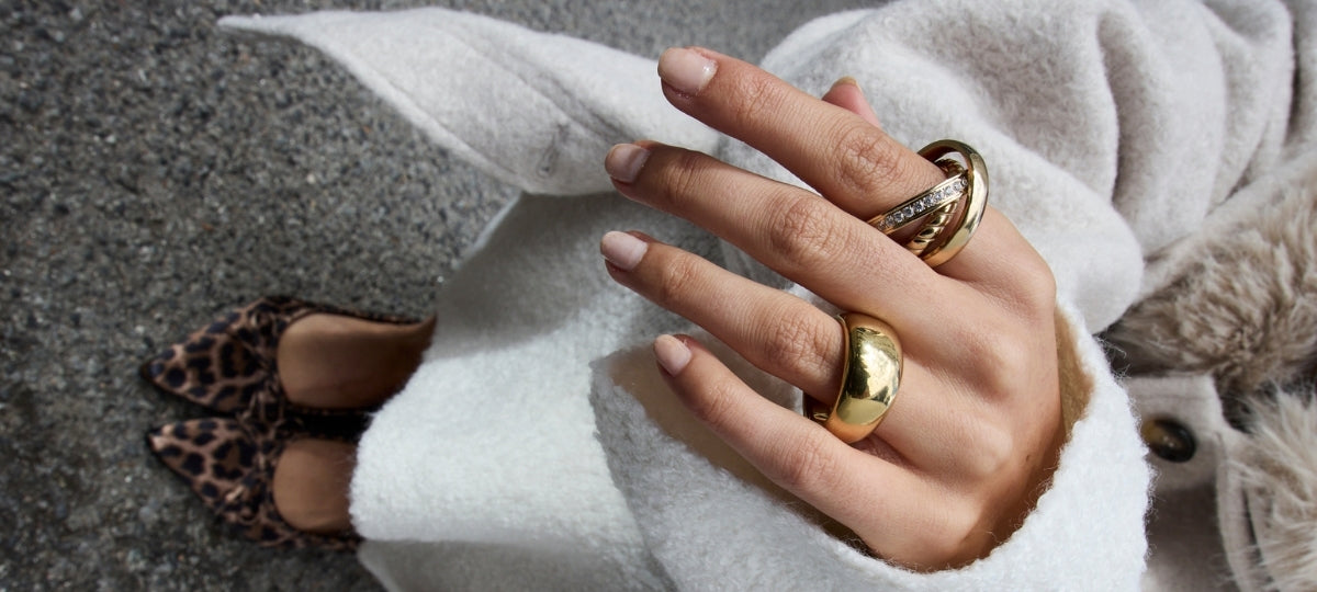 Frau mit goldenen Ringen und Schmuck trägt cremefarbene Strickjacke und Leoparden-Muster Schuhe