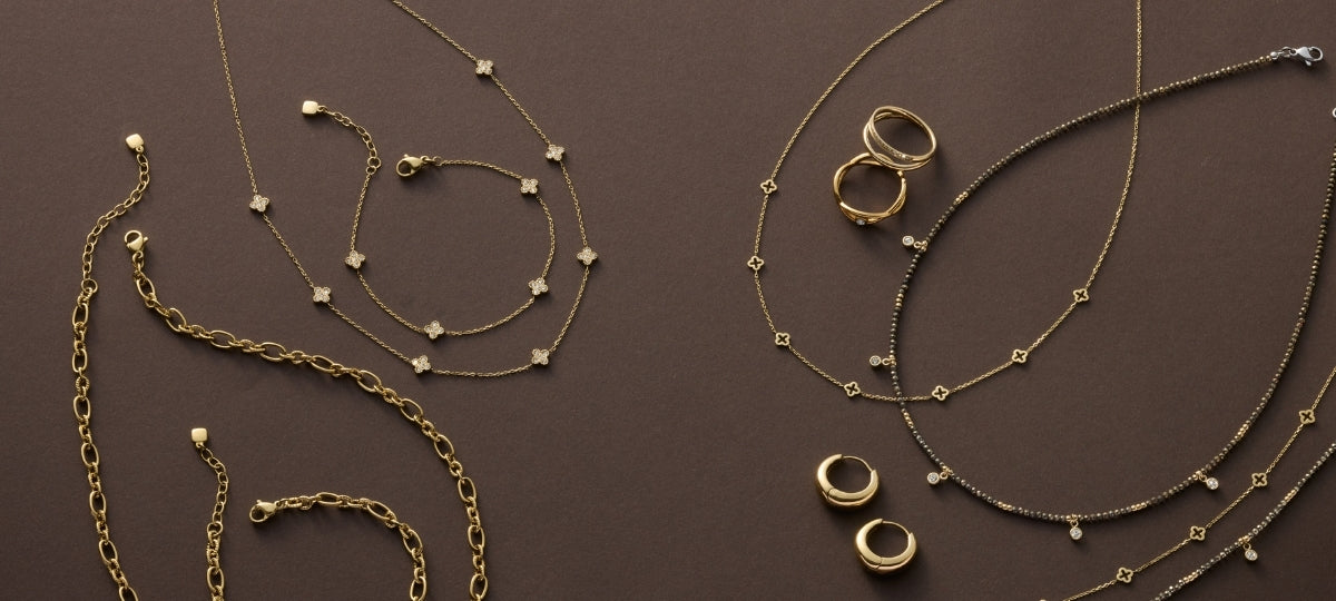 Goldene Halsketten mit Perlen und Ringen, arrangiert auf braunem Hintergrund in eleganter Anordnung