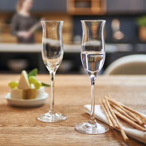 Zwei Grappagläser CHEERS mit Wasser gefüllt auf gedecktem Tisch in Küche